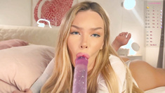 Busty blonde amateur moans in pleasure as she uses a long purple toy in her mouth